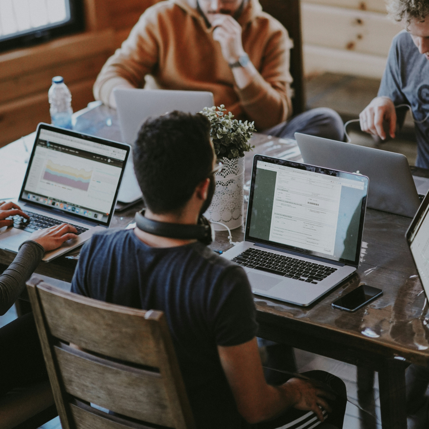 Four people working on laptops around a table