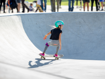 A young girl rides a skate board in a skate park