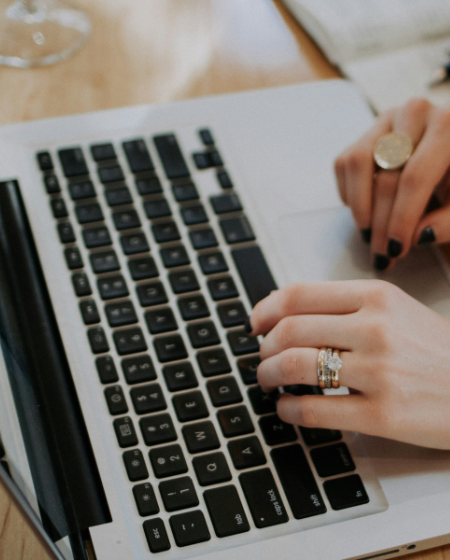 A close up of a woman's hands typing on a laptop